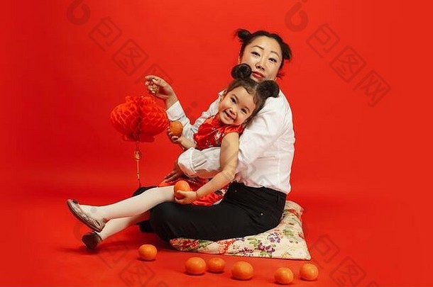 拥抱，开心地微笑，拿着灯笼。2020年中国新年快乐。传统服装红色背景上的亚洲母女肖像。庆祝，人类情感，节日。空间。
