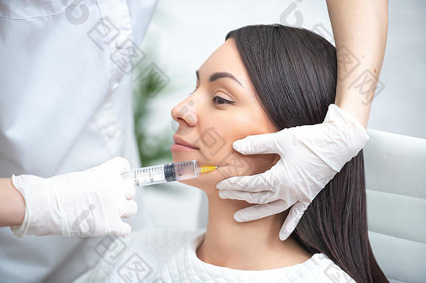 面部填充物注射。整形美容面部手术。女医生用注射器在眼睛周围注射嘴唇和肉毒杆菌。