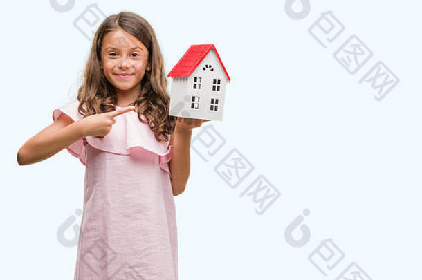 黑发拉美裔女孩抱着小房子非常高兴地用手和手指指着