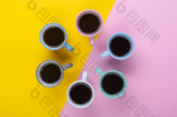 在粉红色和黄色的背景上，美式咖啡在不同的杯子里。平躺，愉快的一天概念。这张图片可以用来显示咖啡休息时间