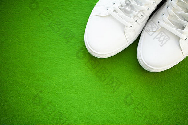 一双绿色背景的新款时尚白色运动鞋。