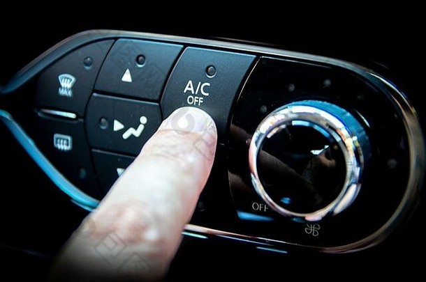 按汽车仪表板上空调按钮的手指