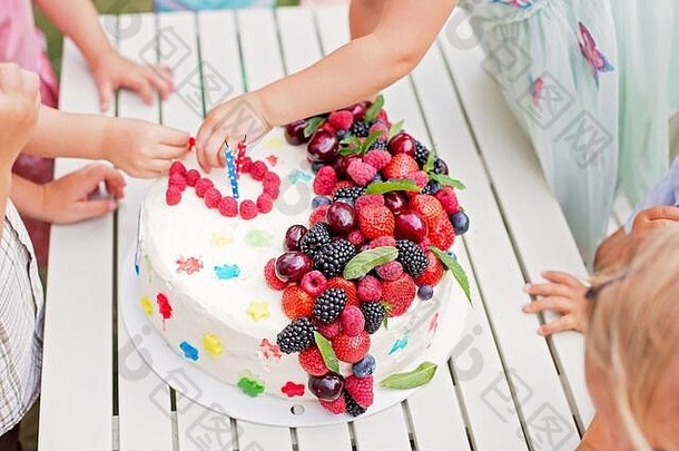 孩子们手吃水果糖果生日蛋糕在户外