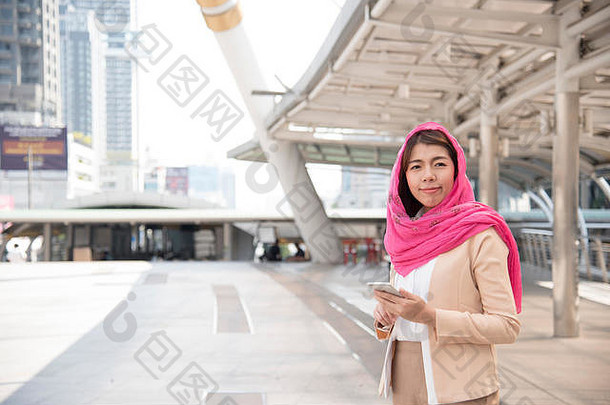 美丽的现代阿拉伯女商人穿戴移动电话大城市