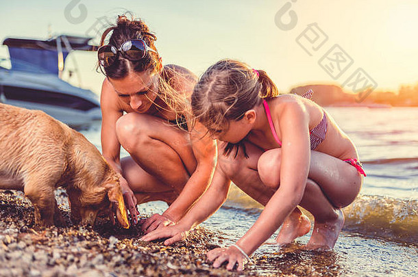 妈妈、女儿和小黄狗在海滩上嬉戏