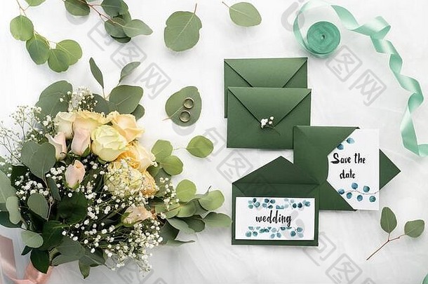 新娘花束和婚礼请柬装在时尚的深绿色信封中