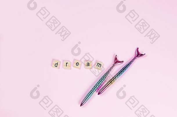 题词“梦想”由一个木制字母和一支时髦的钢笔组成，以粉色背景上的美人鱼尾巴为形式，构思“大梦想”，空间，以