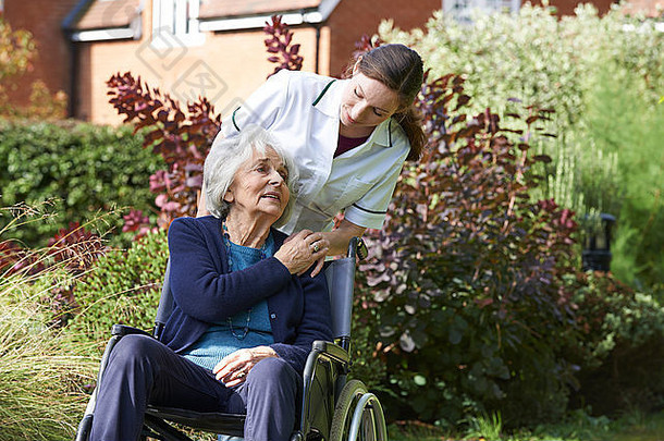 护工推着轮椅上的老年妇女