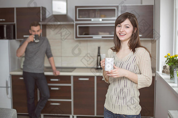 年轻的夫妇站厨房喝咖啡
