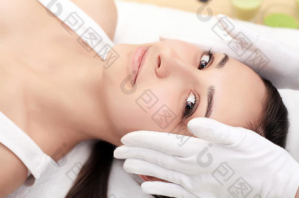皮肤和身体护理。一位年轻女子在美容院接受水疗的特写镜头。Spa面部按摩。面部美容治疗。温泉沙龙。