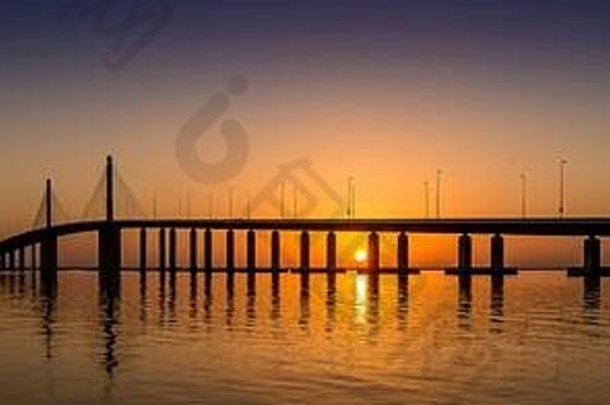 日落时分，阿拉伯联合酋长国阿布扎比的阿尔-巴滕大桥，其轮廓反射在水面上
