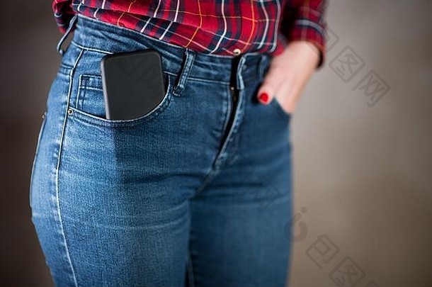 从女孩牛仔裤口袋里伸出的黑色<strong>手机壳</strong>的特写镜头