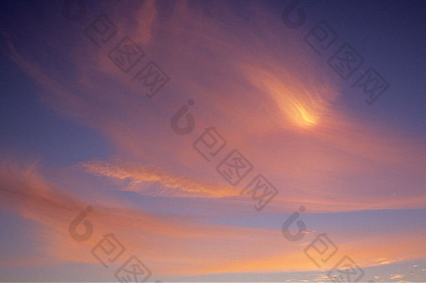 薄薄的卷云被吹成鸟一样的形状，在夕阳下发出粉红色和橙色的光芒