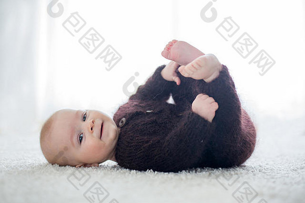 可爱的婴儿男孩穿着手工制作的针织棕色（的）泰迪熊玩首页阳光明媚的卧室