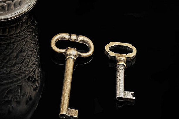 青铜复古钥匙。黑色背景上的两把旧的小青铜钥匙。股票形象。