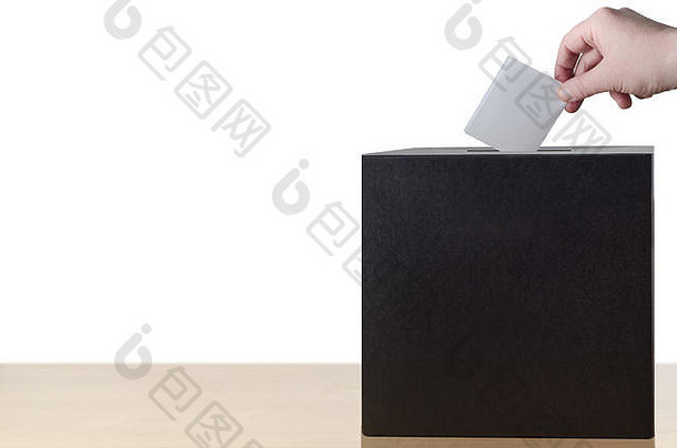 用手将折叠好的投票单放入轻木桌上投票箱的插槽中。在白色背景上隔离。