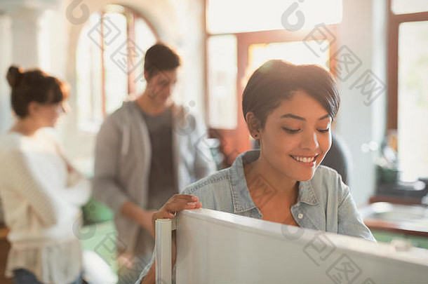 微笑的年轻女子看着厨房里的冰箱