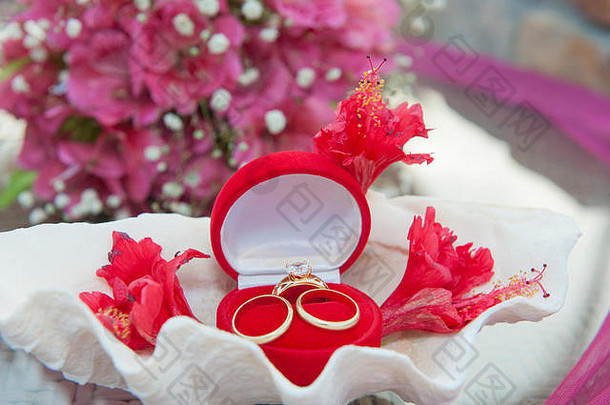 红色天鹅绒首饰盒中的三枚金婚戒和钻石戒指