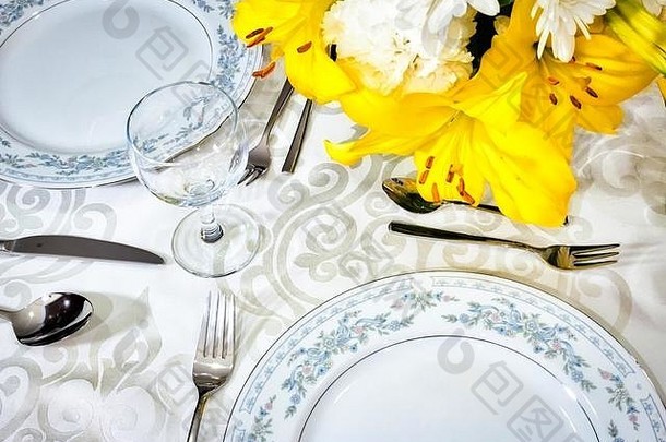 在一家<strong>高档餐厅</strong>里，白色桌布上摆放着精美的餐具，桌上的花瓶里摆放着鲜花，为浪漫的一餐提供优雅的用餐环境