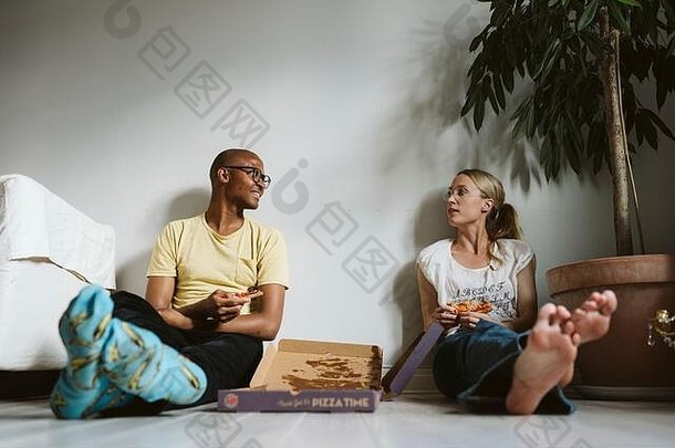 一对夫妇坐在地板上吃比萨饼