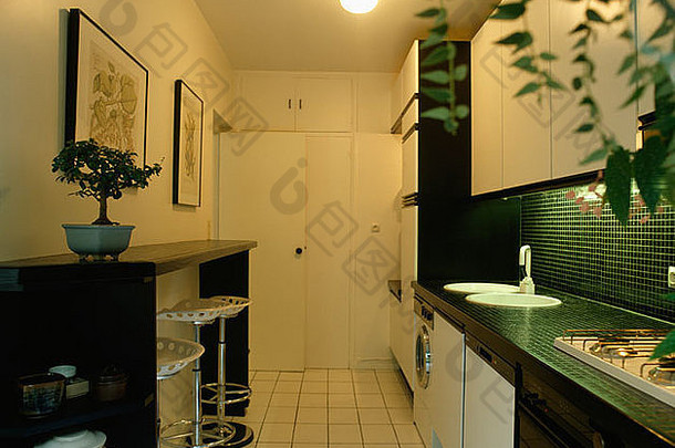 厨房黑色早餐吧的不锈钢凳子，白色地砖和黑色台面上的白色水槽