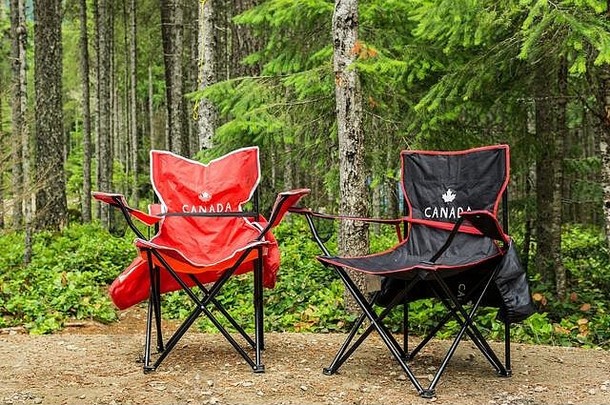 两张露营椅在绿林中的露营地上。