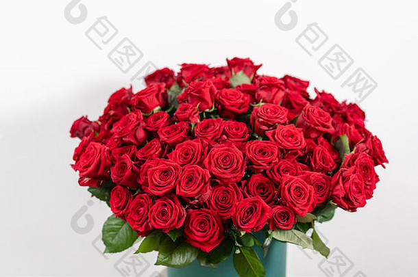 木制桌子上有一个巨大的豪华明亮的花束。一百朵花园里的红玫瑰。色彩深红，秋意盎然。帽盒里的花束