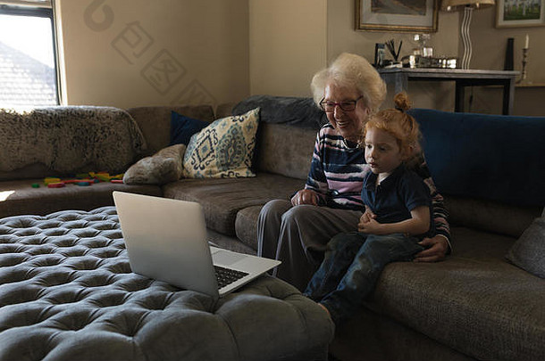 祖母和孙女在客厅用笔记本电脑打视频电话