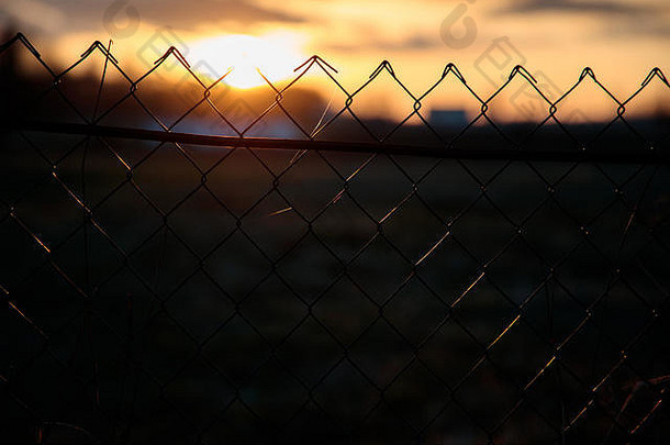 日落背景上的网状栅栏照片