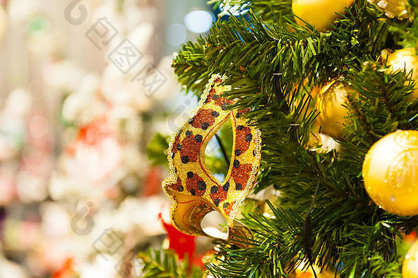 美丽的狂欢节面具挂在圣诞树上，背景是明亮的圣诞装饰