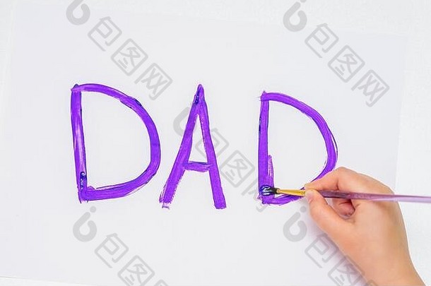 孩子的手在白纸上画紫色单词“爸爸”的俯视图。<strong>父亲节</strong>快乐。