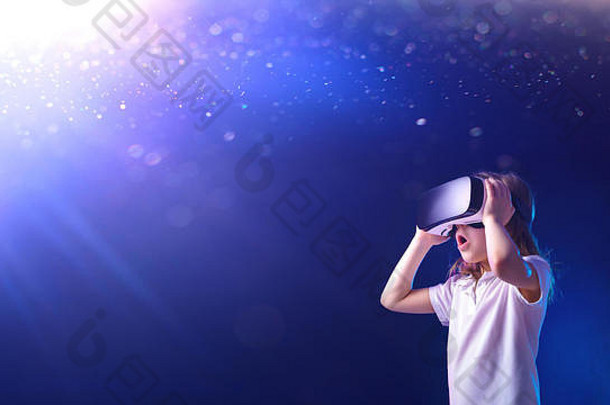 在闪亮的蓝色背景上使用虚拟现实数码眼镜的惊讶女孩儿