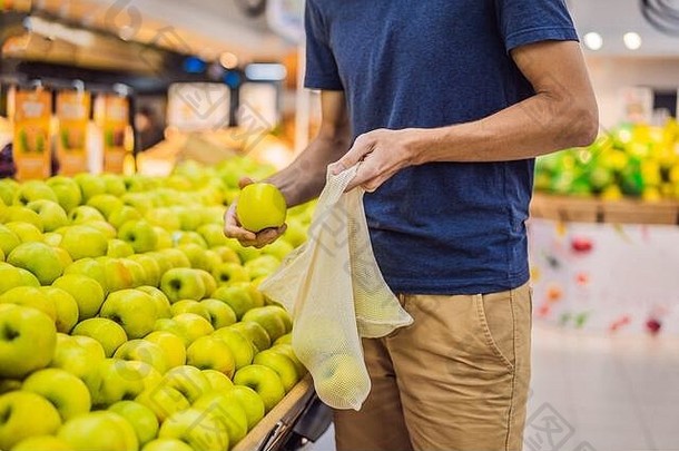 男人。选择<strong>苹果</strong>超市塑料袋可重用的袋购买蔬菜浪费概念