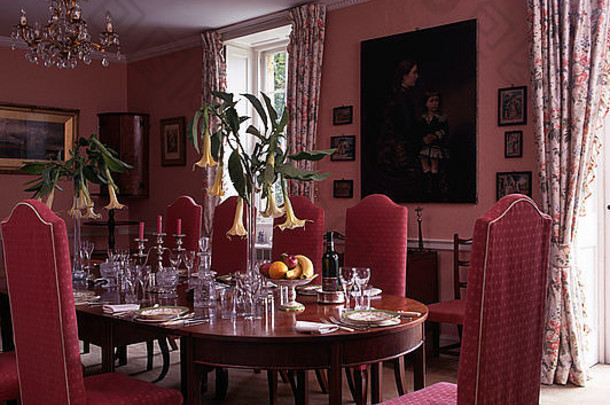 粉红色软垫椅子放在餐桌上，供90年代粉红色餐厅午餐之用，桌上有曼陀罗的高花瓶