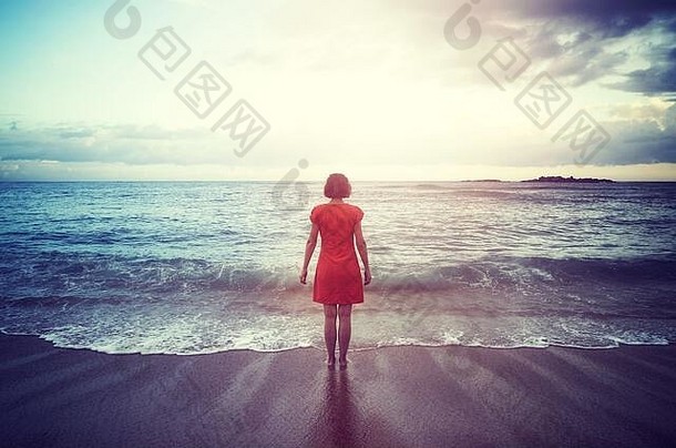 女人站海滩面对地平线日落颜色爽肤水应用
