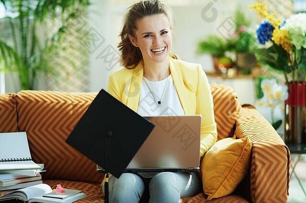 微笑现代学生牛仔裤黄色的夹克毕业帽移动PC现代首页阳光明媚的一天