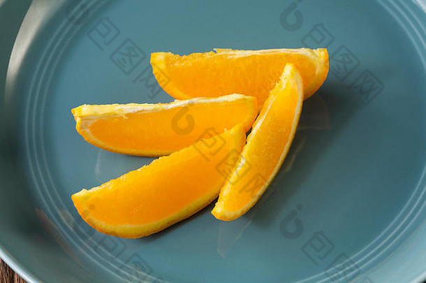 四个橙色的楔子坐在一个蓝色的碗里。