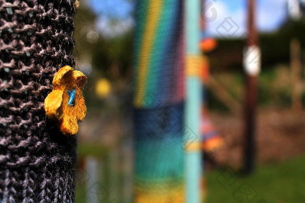 苏格兰奥本，旧电线杆周围有黄色花朵的彩色针织物。