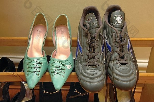 博尔顿，兰开夏郡。一双绿色细高跟鞋和一双灰色足球靴在国际援助慈善商店出售。