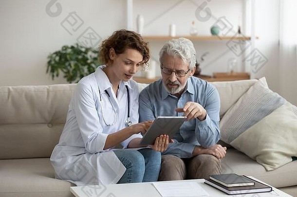 女医生使用数字平板电脑在家咨询老年患者