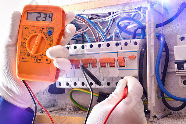 带保护元件的电气工在带测试仪的电气箱内进行电气测量