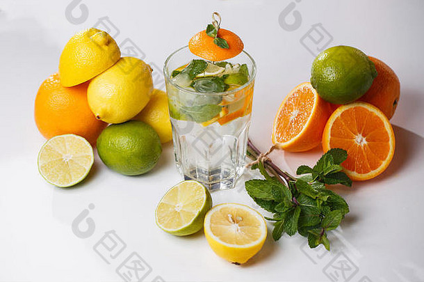 白色桌面上的柠檬、酸橙和薄荷运动杯水