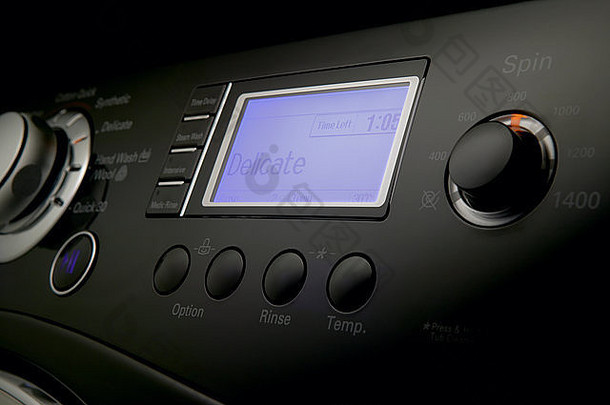 现代洗衣机控制面板和按钮的特写镜头，黑色背景下带有定时器和选项键