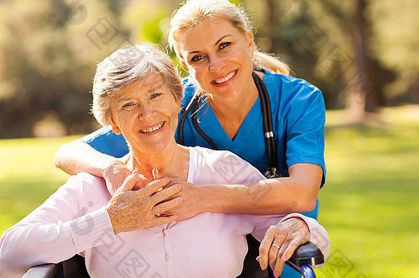 户外轮椅上的快乐老年妇女，带着关爱的护理者