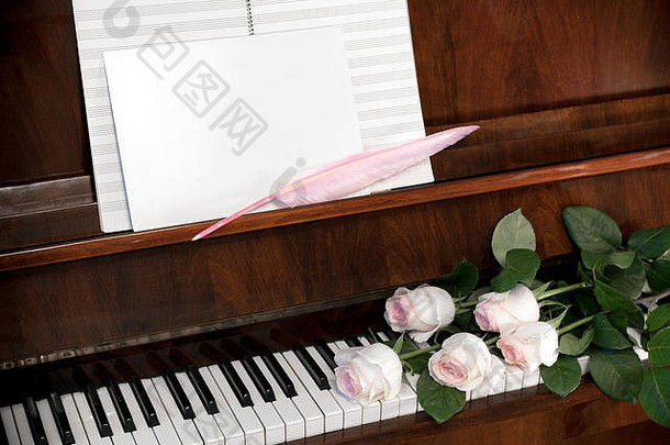 由浅粉色玫瑰、音乐纸和白色空白纸组成，在棕色钢琴上用粉色羽毛笔书写。