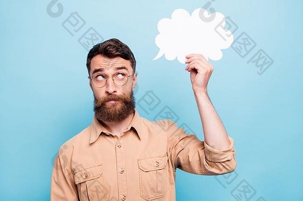 一幅有思想的人举着纸牌看着泡泡的肖像，穿着蓝色背景上隔离的棕色衬衫