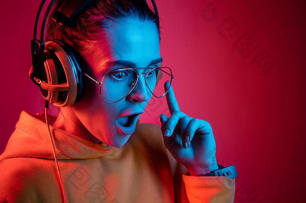时尚漂亮的女人耳机听音乐红色的霓虹灯背景工作室