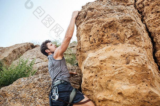 一名男子在陡峭<strong>的</strong>悬崖上攀岩时伸手抓住