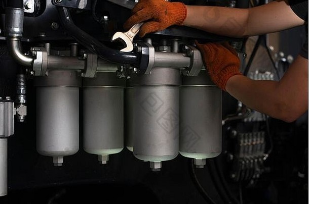 车库重工业机器上液压管道维护的低调照片。