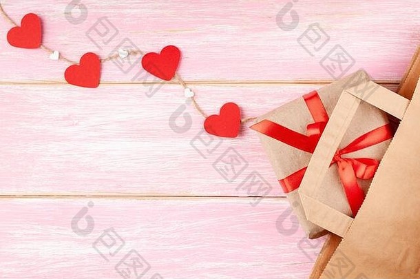 手工纸袋和礼品盒，红色丝带蝴蝶结和心形，粉色背景